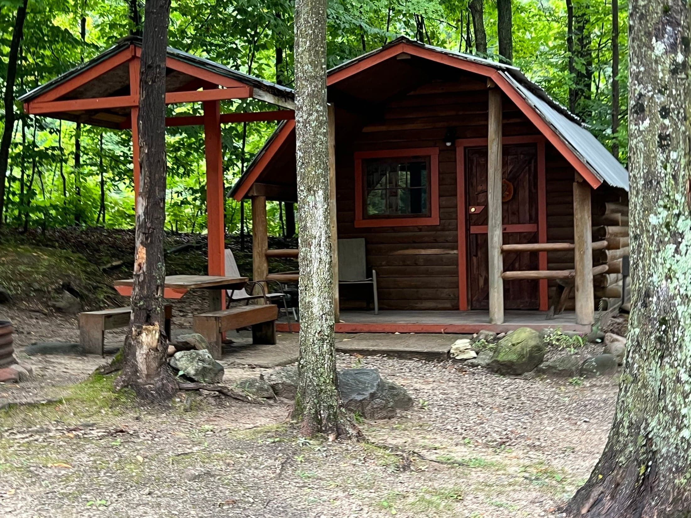 Rustic cabin with covered porch and picnic area in the woods